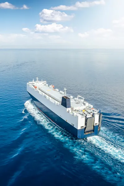 Vessel on open water sailing into calm seas and blue skies