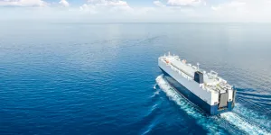 Blue and white ship at sea with blue sky and clouds
