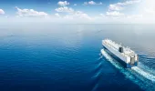 Vessel on open water sailing into calm seas and blue skies