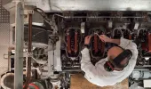 A seafarer wearing ear defenders at work on a ship engine