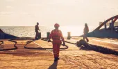 Seafarers working on a vessel at sunset
