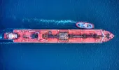 Red tanker with a tug boat at the side of the ship