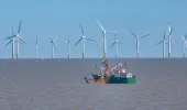Fishing vessel at sea with offshore wind farm in background